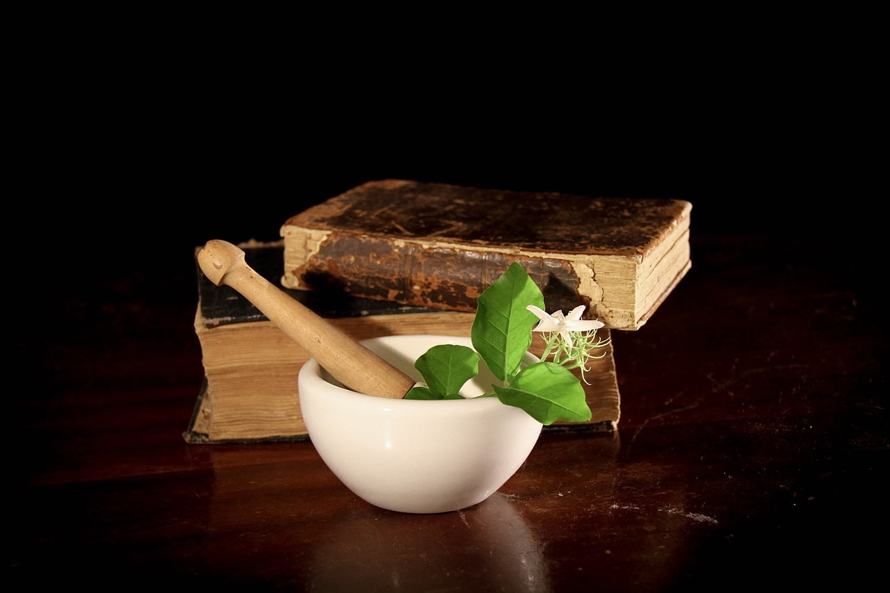 Old books and bowl with herbs