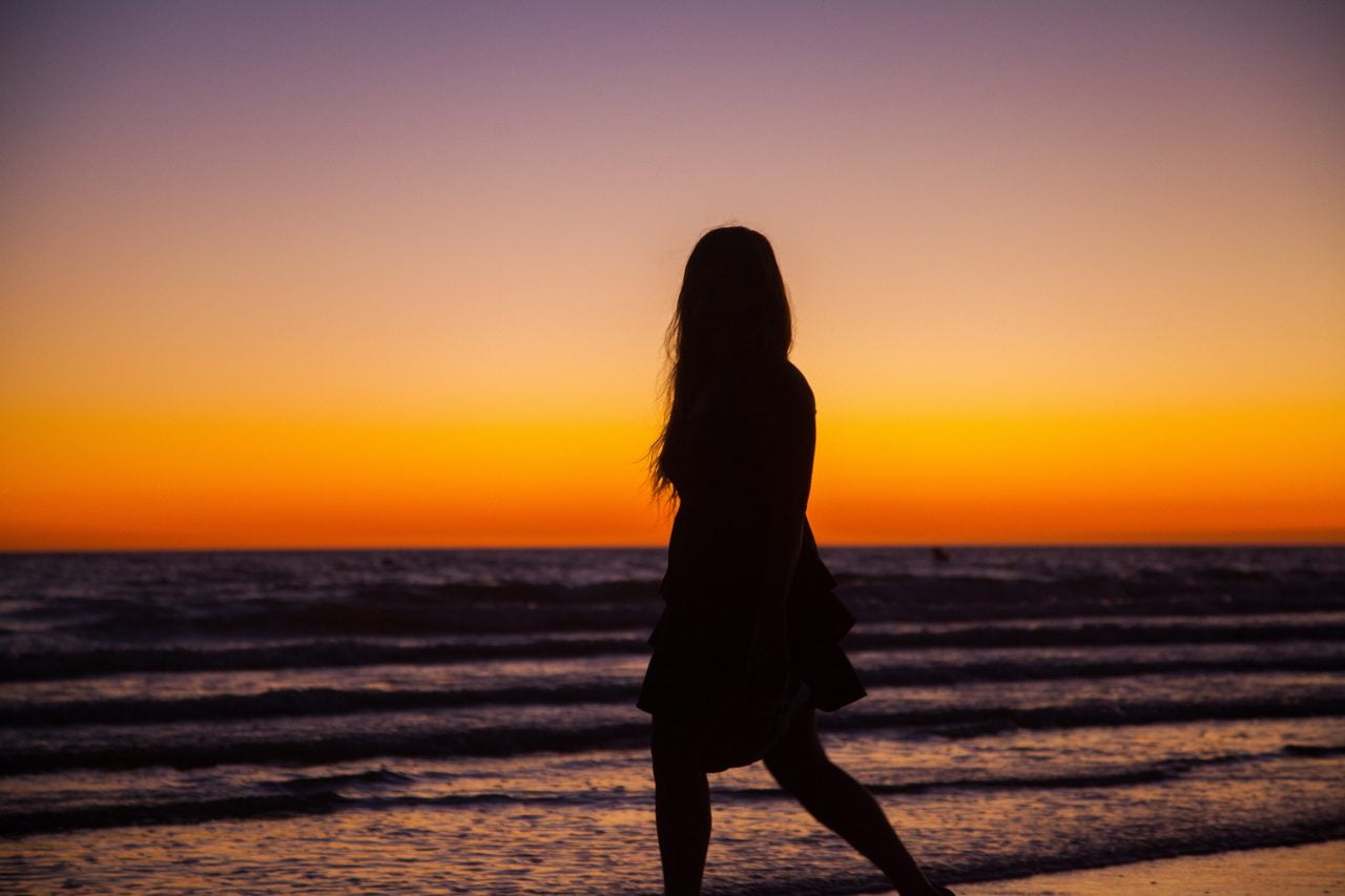 Woman Walking on Beach at Sunset