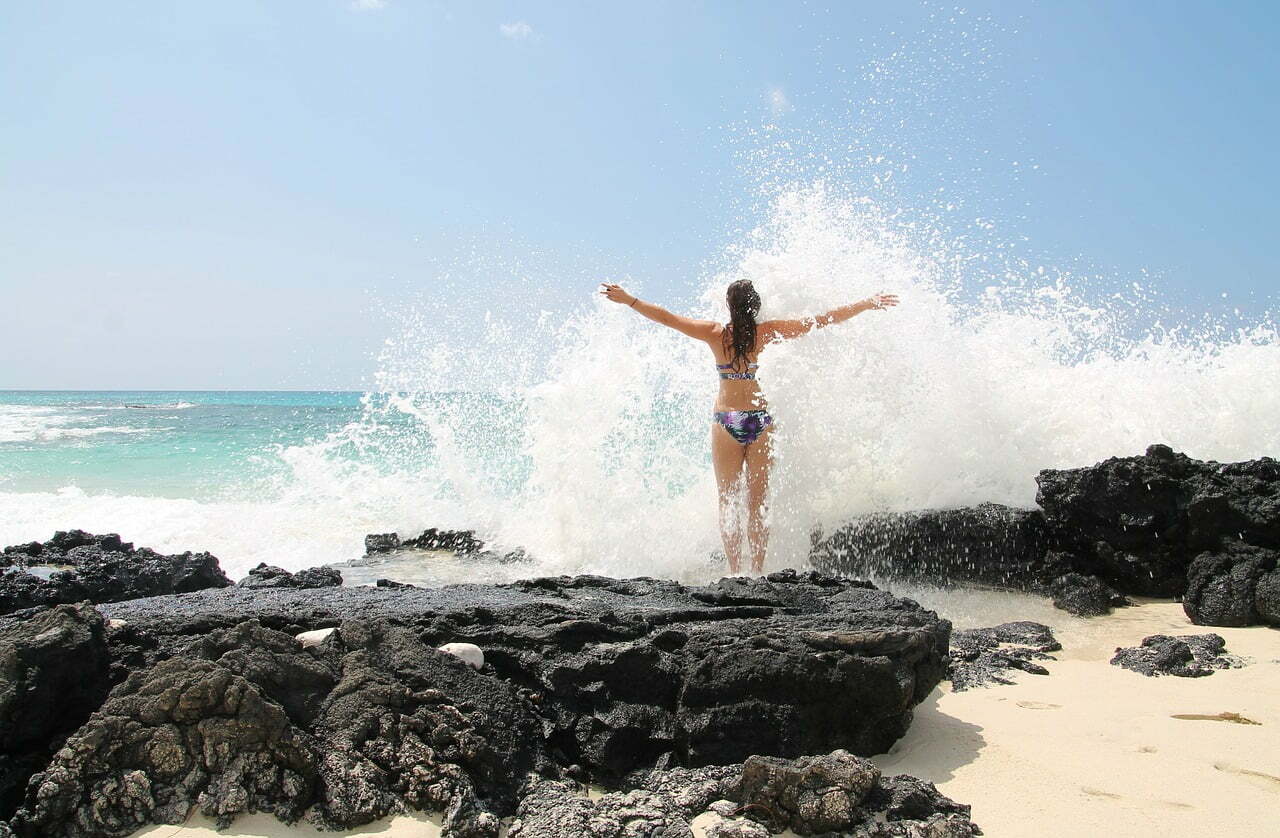 Woman on beach getting splashed by waves