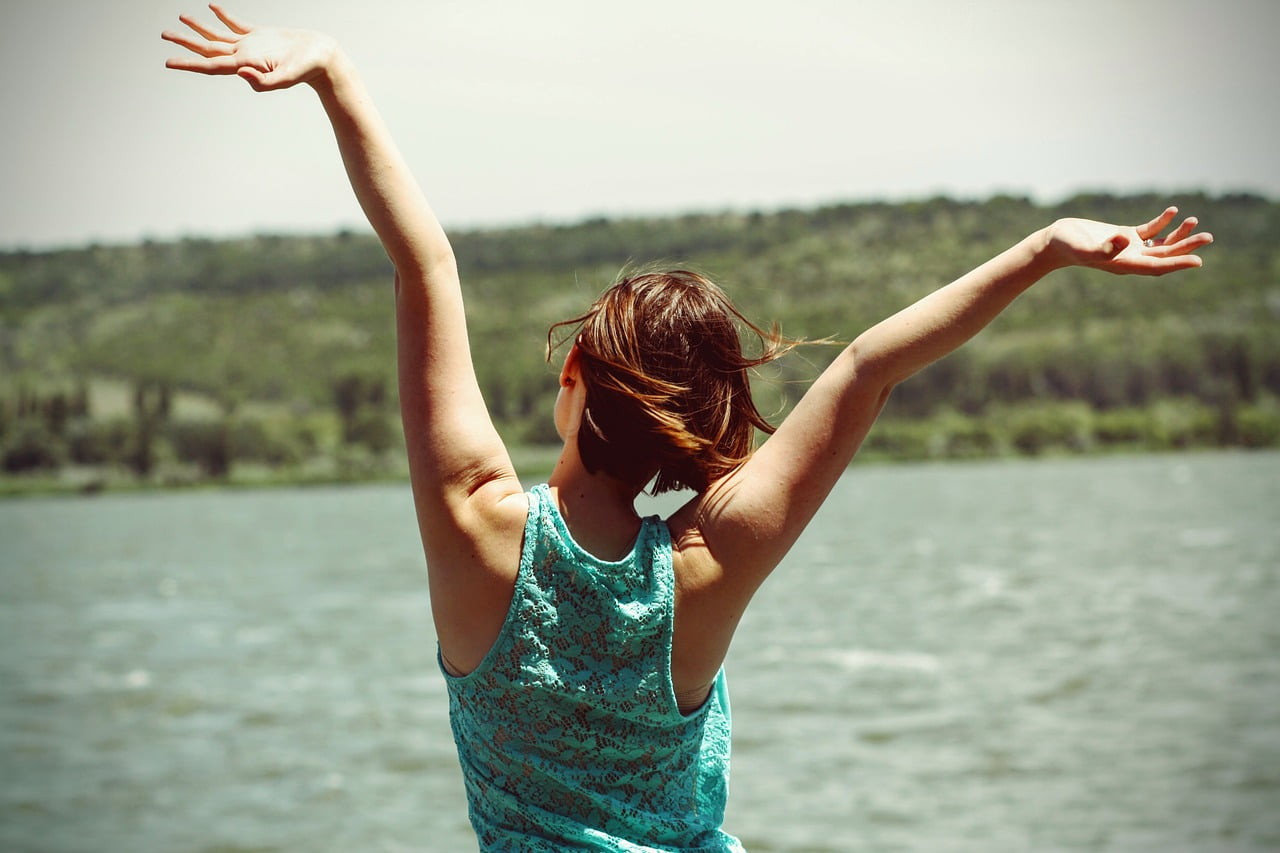 woman hands up near water