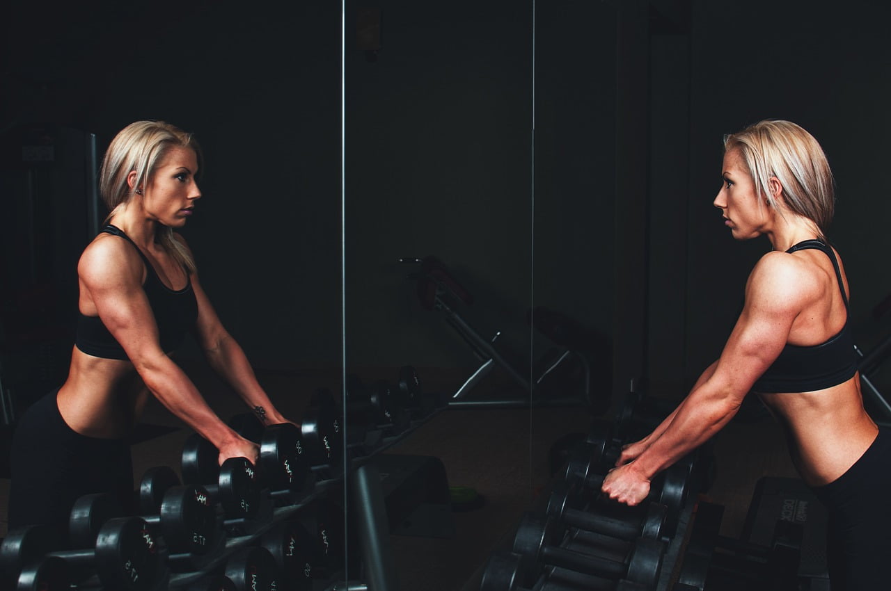 woman dumb bells looking in mirror