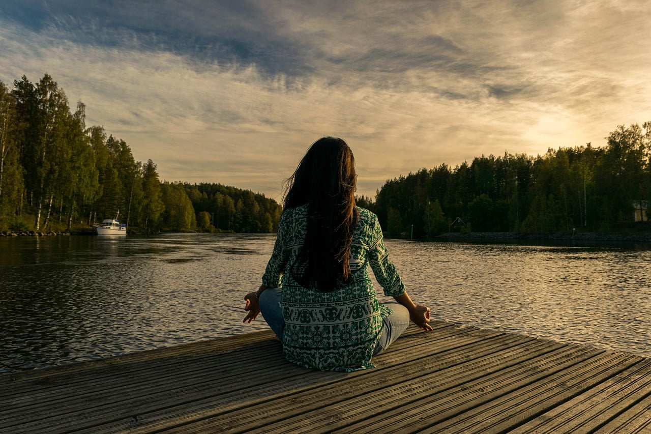 woman meditating near water