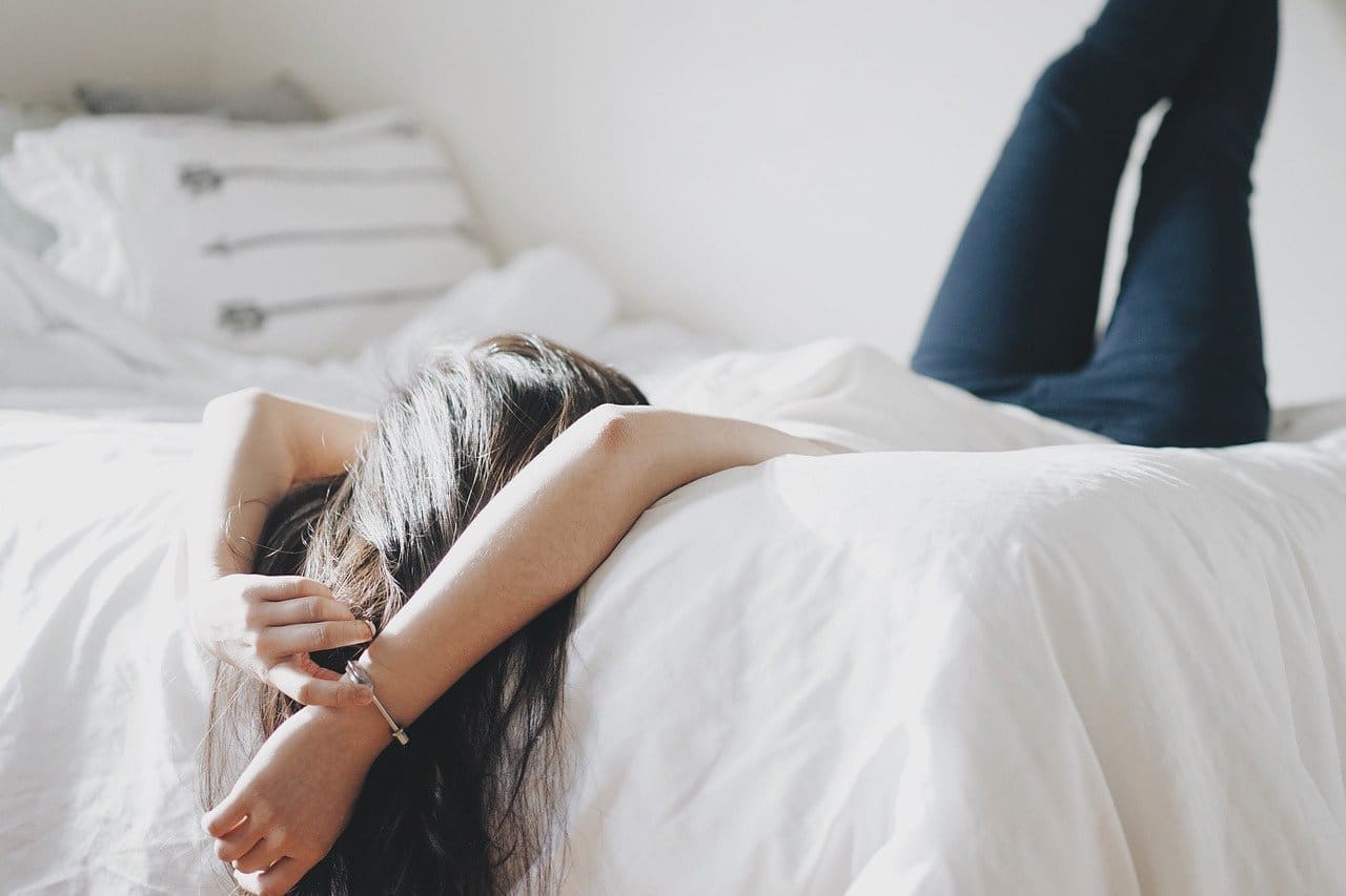 Woman Laying in Bed - Leaning Feet Against Wall