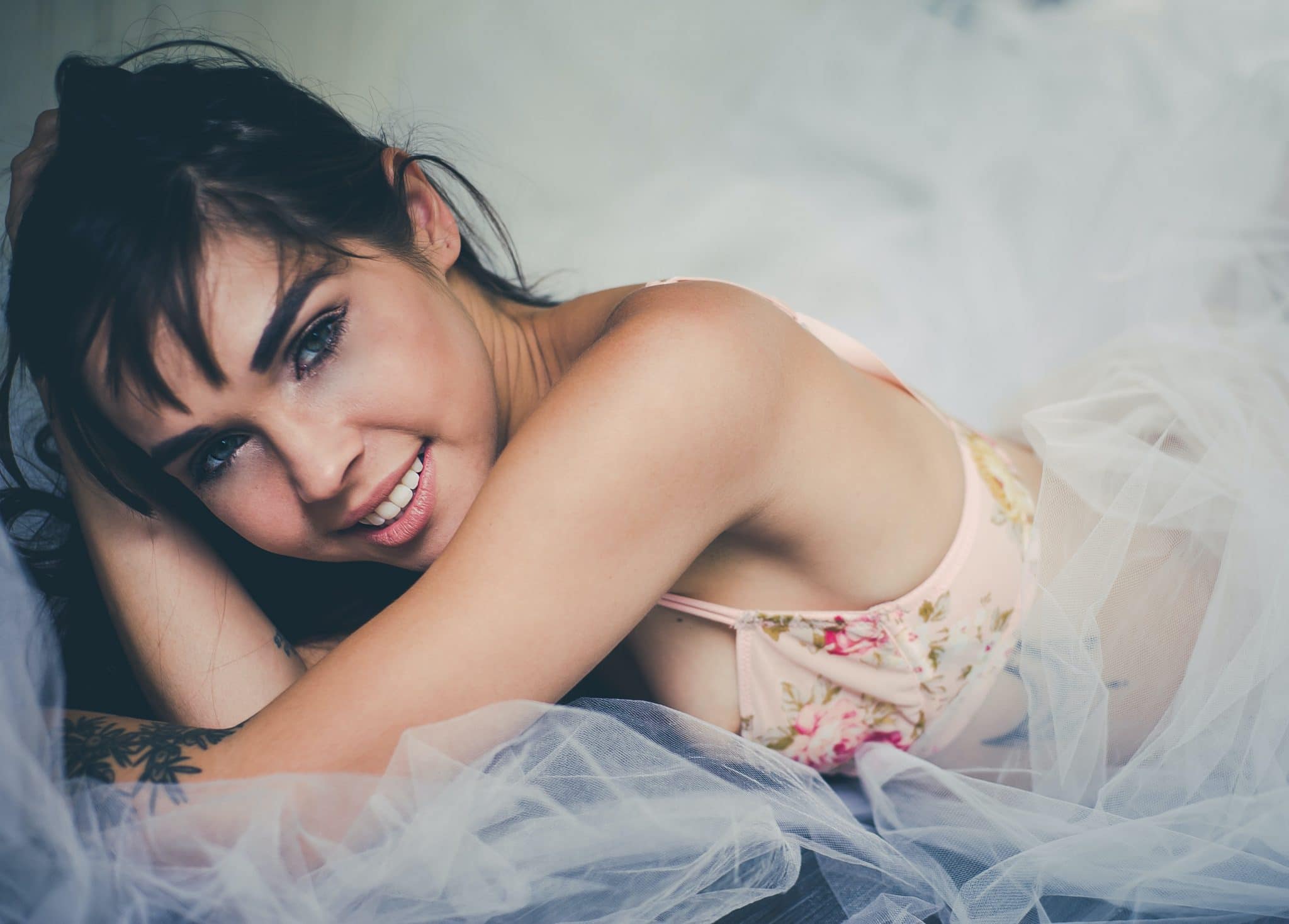 A smiling woman wearing a pink floral bra