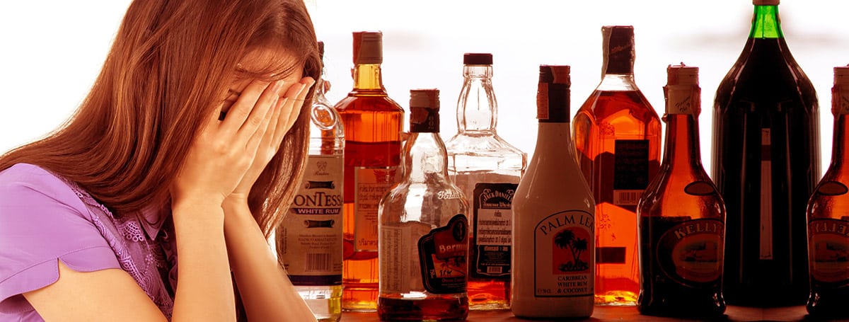 Woman next to various bottles of alcohol